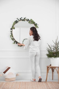 Evde okaliptüs dallarıyla ayna dekore eden kadın.