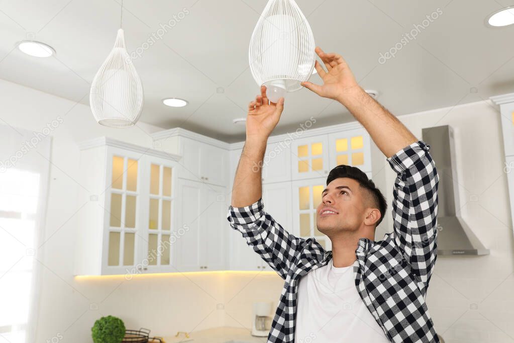 Man changing light bulb in lamp at home. Space for text