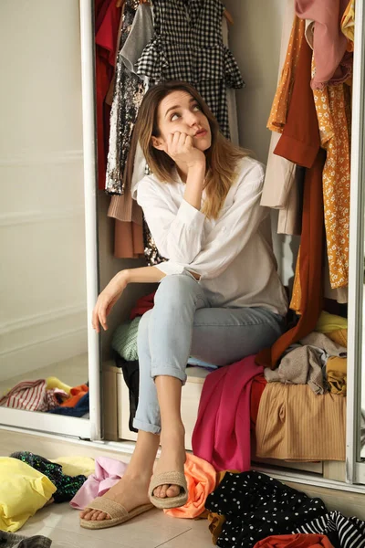 Jovem Mulher Sentada Guarda Roupa Com Roupas Diferentes Dentro Casa — Fotografia de Stock