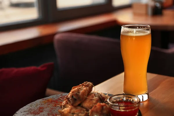 Fresh beer and tasty BBQ wings served on wooden table