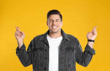 Sarı arka planda çapraz parmaklı bir adam. Batıl inanç kavramı