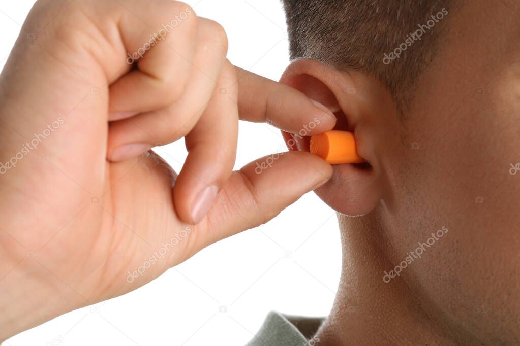 Man inserting foam ear plug on white background, closeup