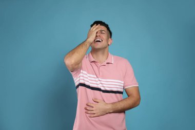 Açık mavi arka planda gülen yakışıklı bir adam. Komik şaka.