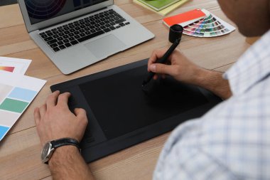 Ahşap masada grafik tableti olan profesyonel tasarımcı, yakın plan.