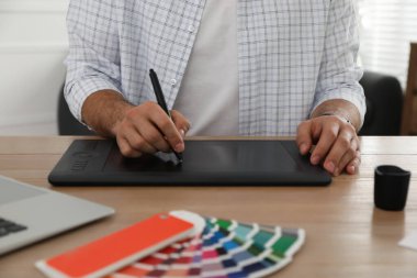 Ahşap masada grafik tableti olan profesyonel tasarımcı, yakın plan.