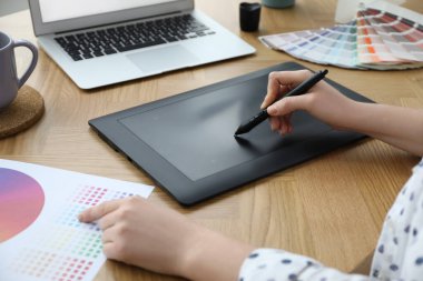 Ahşap masada grafik tableti olan profesyonel tasarımcı, yakın plan.