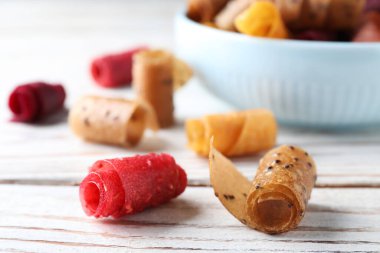 Lezzetli meyve derisi beyaz ahşap masada yuvarlanıyor, yakın plan.