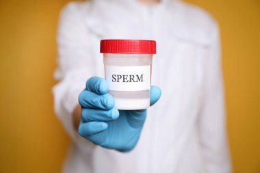 Sarı arka planda spermi olan bir bilim adamı yakın plan.