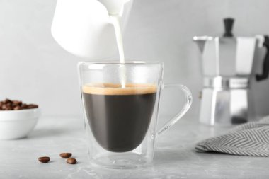 Gri mermer masada aromatik kahve ile sütü fincana dökerek.