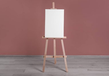 Tozlu gül duvarının yanında boş tuval olan ahşap sehpa