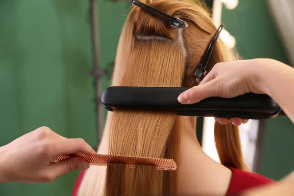 发型师在沙龙里用扁平的熨斗直女人的头发 — 图库照片