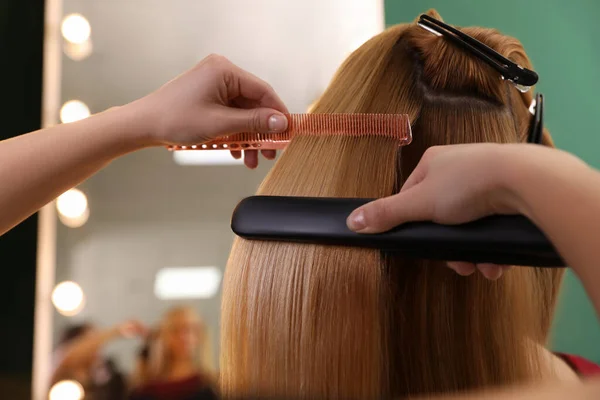 发型师在沙龙里用扁平的熨斗直女人的头发 — 图库照片