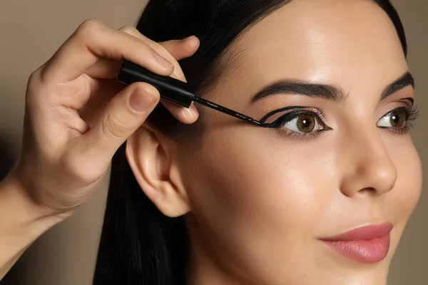 Καλλιτέχνης Εφαρμογή Μαύρο Eyeliner Στο Πρόσωπο Της Γυναίκας Μπεζ Φόντο — Φωτογραφία Αρχείου