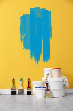 Dekoratör aletleri ve sarı duvarın yanındaki zemine boya döşeme.