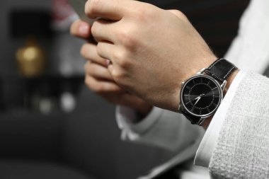 Bulanık arka planda lüks kol saati olan bir iş adamı. Yakın plan.