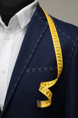 Manken üzerinde terzi ölçüm bandı olan yarı hazır ceket, yakın plan.
