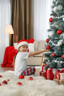 Evde Noel ağacı süsleyen tatlı küçük kız.
