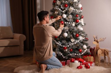 Evdeki güzel Noel ağacını süsleyen adam.