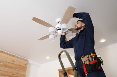 Elektrikçi tavan vantilatörünü içeride lambayla onarıyor. Metin için boşluk