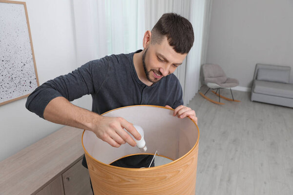 Man changing light bulb in lamp at home