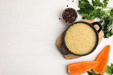 Beyaz ahşap masada tavada kuru pirinçle bezenmiş düz bir kompozisyon. Metin için boşluk