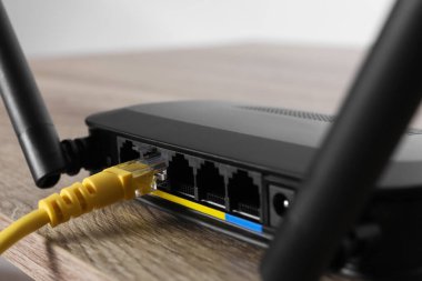 Tahta masadaki yönlendiriciye bağlı kablo, yakın plan. Kablosuz internet iletişimi