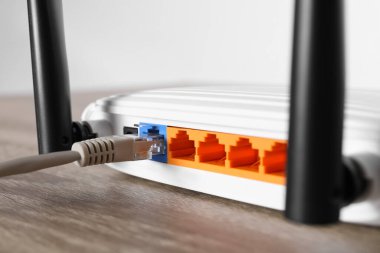 Tahta masadaki yönlendiriciye bağlı kablo, yakın plan. Kablosuz internet iletişimi