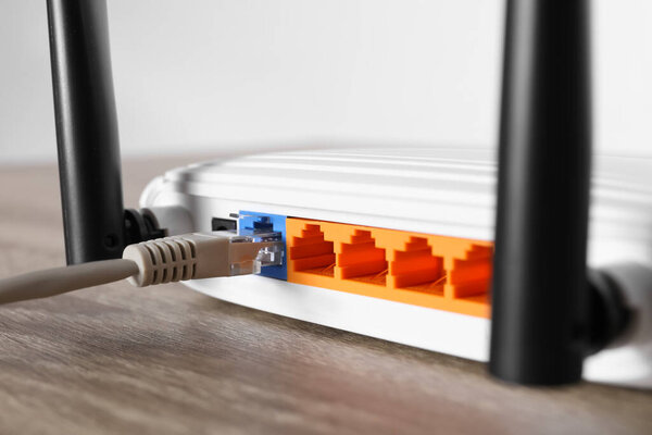 Подключен кабель к маршрутизатору на деревянном столе, крупным планом. Беспроводной интернет