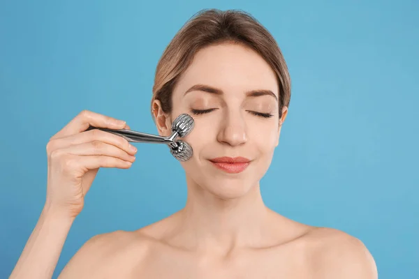 Ung Kvinna Som Använder Metall Ansikte Roller Ljusblå Bakgrund — Stockfoto