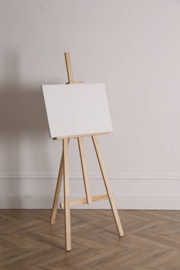 Işık duvarının yanında boş tuval olan ahşap sehpa
