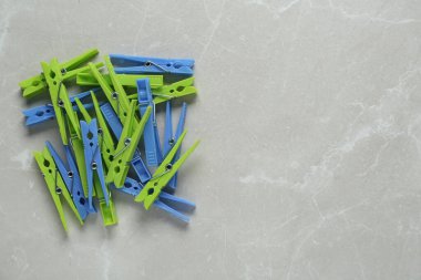 Açık gri mermer zemin üzerinde renkli plastik mandallar, düz zemin. Metin için boşluk