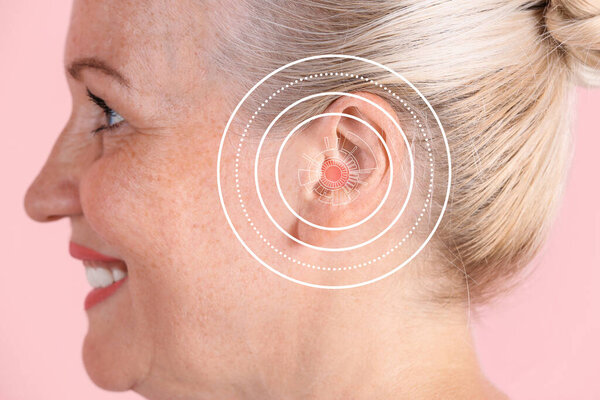 Mature woman with hearing problem on pink background, closeup 