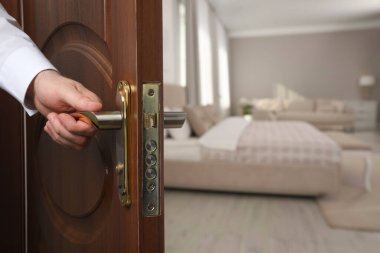 Adam otel odasının ahşap kapısını açıyor, yakın plan.