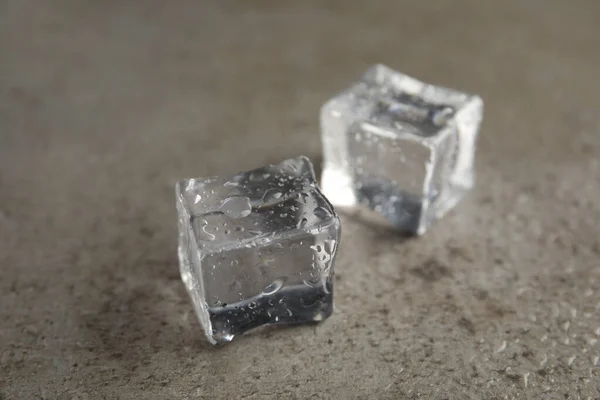 灰色の石のテーブルの上に水が落ちる氷のキューブ クローズアップ — ストック写真