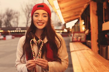 Genç bir kadın Noel fuarında vakit geçiriyor.