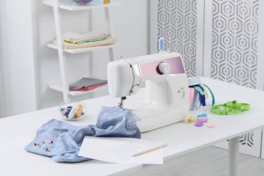 Modern dikiş makinesi, kumaş ve aksesuarlar masa içinde.