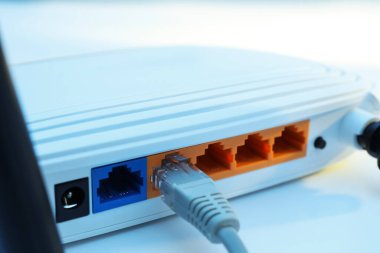 Beyaz masadaki yönlendiriciye bağlı kablo, yakın plan. Kablosuz internet iletişimi
