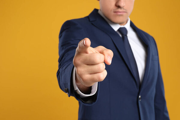 Businessman touching something on yellow background, closeup. Finger gesture