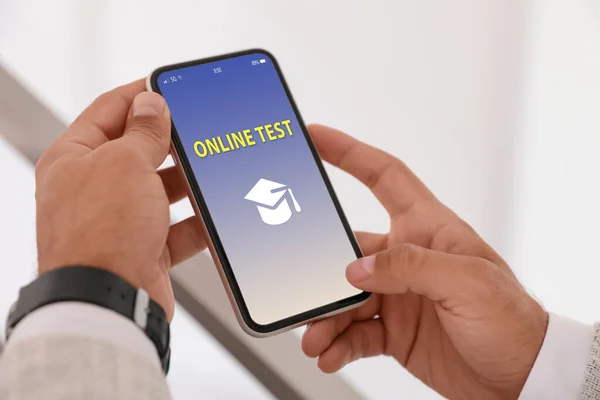 Man using smartphone for online test indoors, closeup