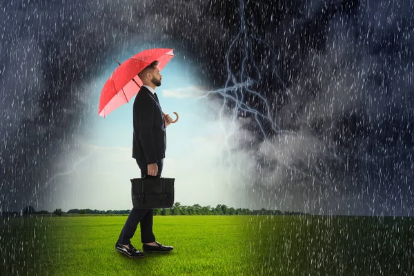 Businessman with umbrella under heavy rain. Insurance concept