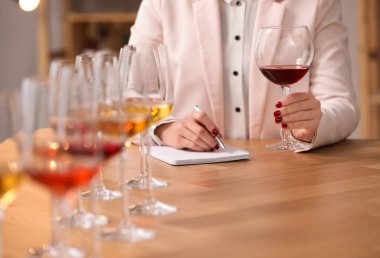 Sommelier içerideki masada farklı türde şarap tadıyor, yakın plan.