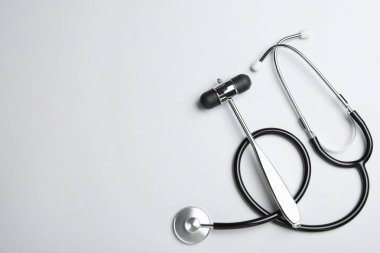 Beyaz arka planda steteskoplu refleks çekici, düz yatış ve metin için boşluk. Sinir sistemi tanılama