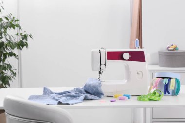 Modern dikiş makinesi, kumaş ve aksesuarlar masa içinde.
