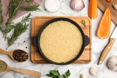 Düz kompozisyon ve kuru pirinç beyaz mermer masa üzerinde wok