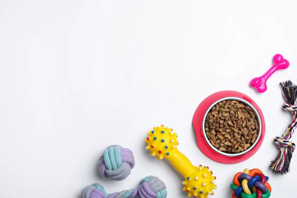 Different pet toys and feeding bowl on white background, top view. Space for text