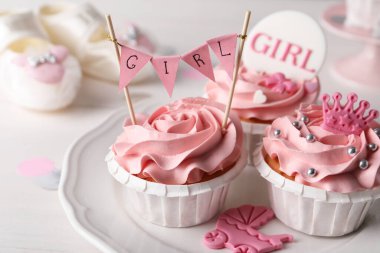 Pembe kremalı lezzetli kekler ve tabakta bebek partisi için kaplar, yakın plan.
