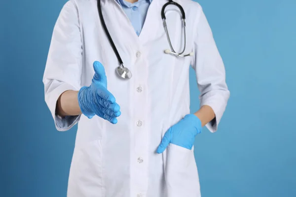 Kvinna Läkare Handskar Som Erbjuder Handslag Ljusblå Bakgrund Närbild — Stockfoto