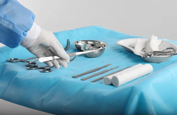 Lekarz Trzymający Kleszcze Nad Stołem Przyrządami Chirurgicznymi Jasnym Tle Zbliżenie — Zdjęcie stockowe