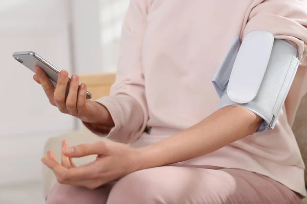 Frau Kontrolliert Blutdruck Mit Modernem Monitor Und Smartphone Haus Nahaufnahme — Stockfoto