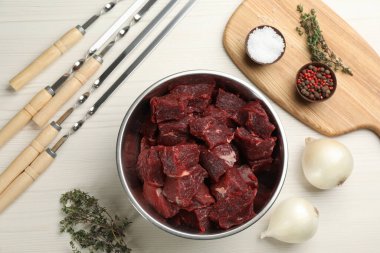 Düz kompozisyon, metal şişler ve beyaz ahşap masa üzerinde taze et.